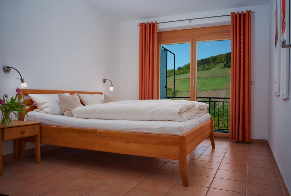 Schlafzimmer der Ferienwohnung am Weingut Arns in Reil mit Doppelbett, Balkon und Blick auf die Weinberge an der Mosel
