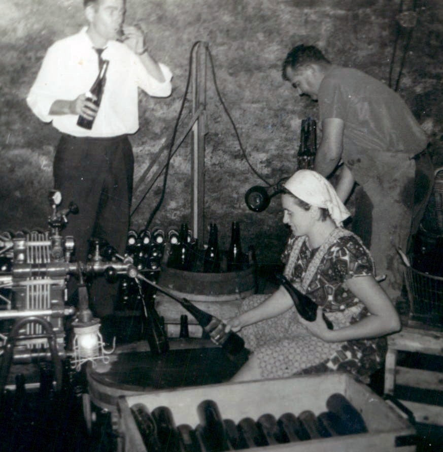 Besucher aus der Stadt kosten Wein während der Flaschenabfüllung im Weinkeller – historisches Foto Weingut Arns